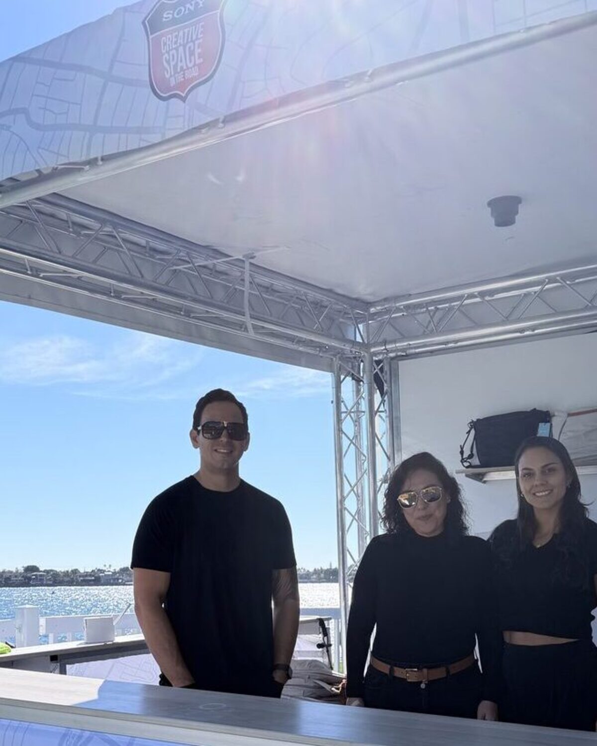Merch Troop crew running an open-air live-printing booth beside San Diego Bay under a clear blue sky