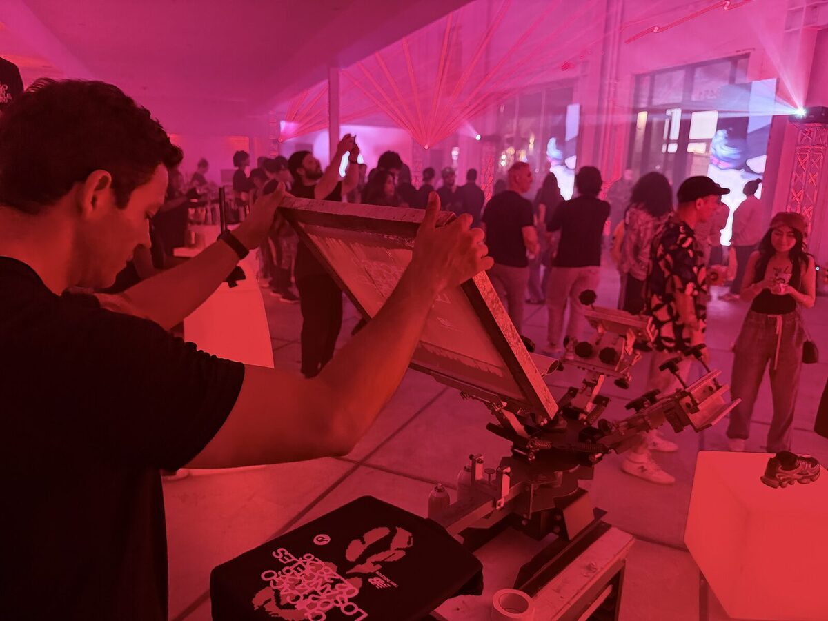 A Merch Troop printer pulling a print on a multi-color press during a high-energy evening event
